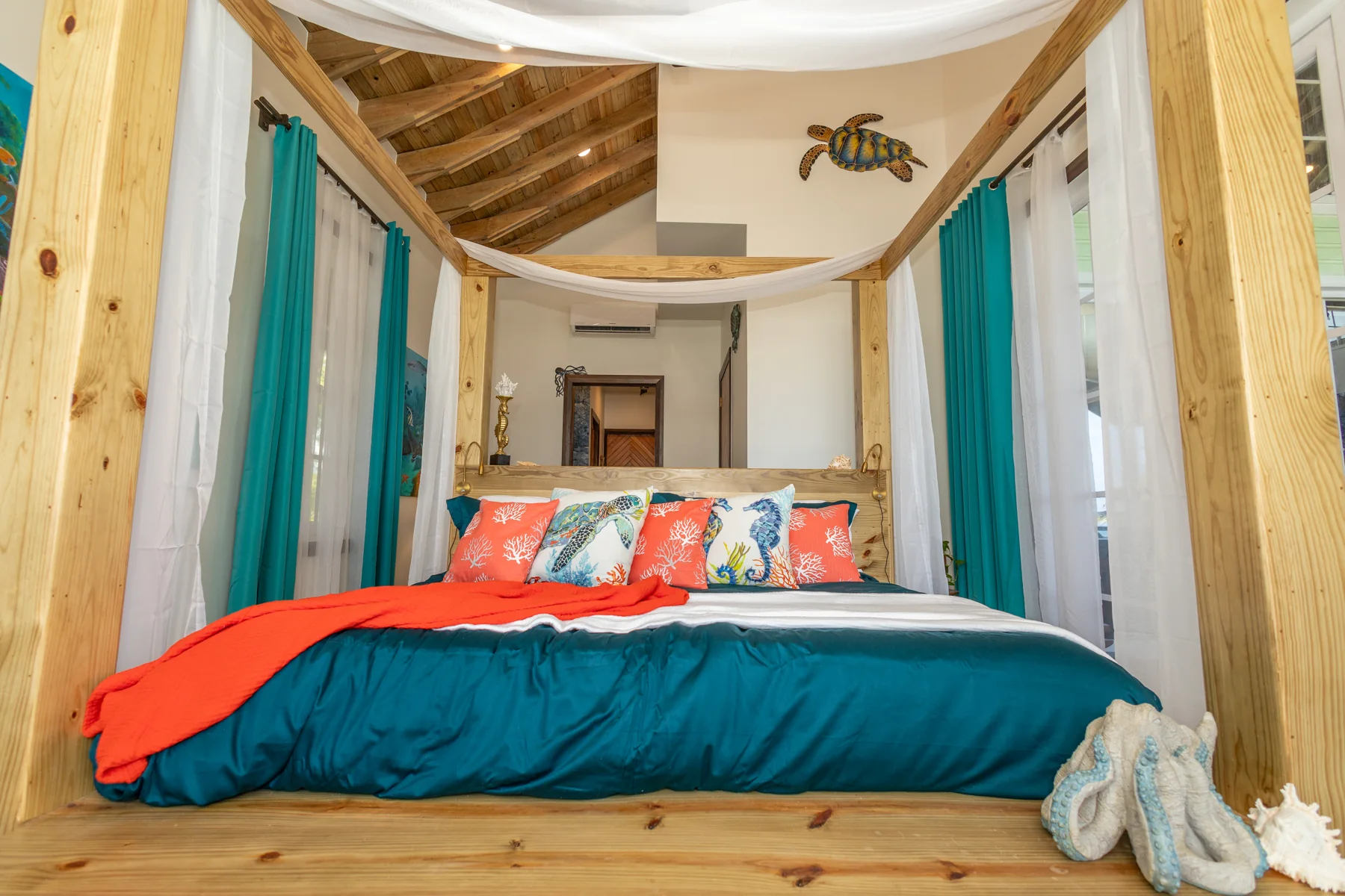 Ocean Room bed with turquoise bedding, exposed timber, and canopy curtains
