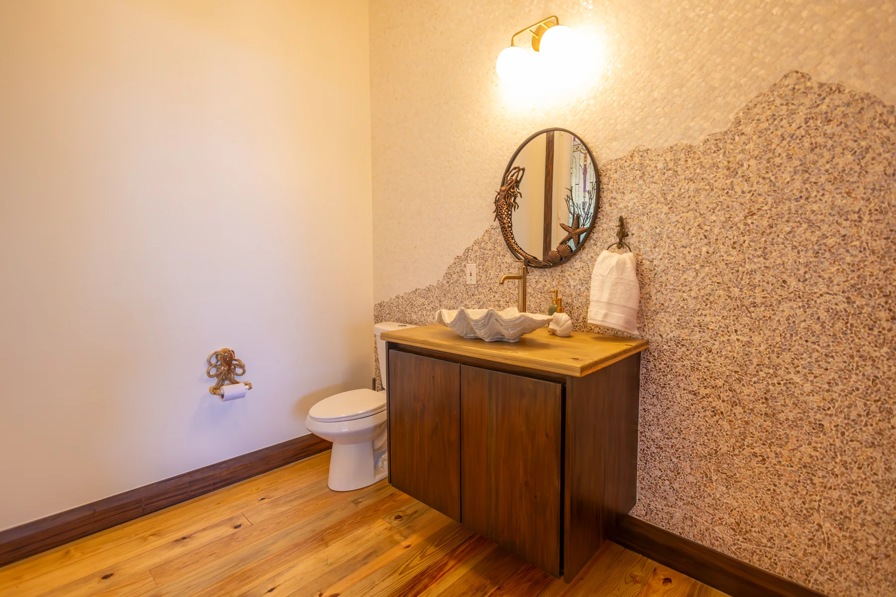 Sea Shell half bath off the main room with shell-patterned wall, vanity, and toilet