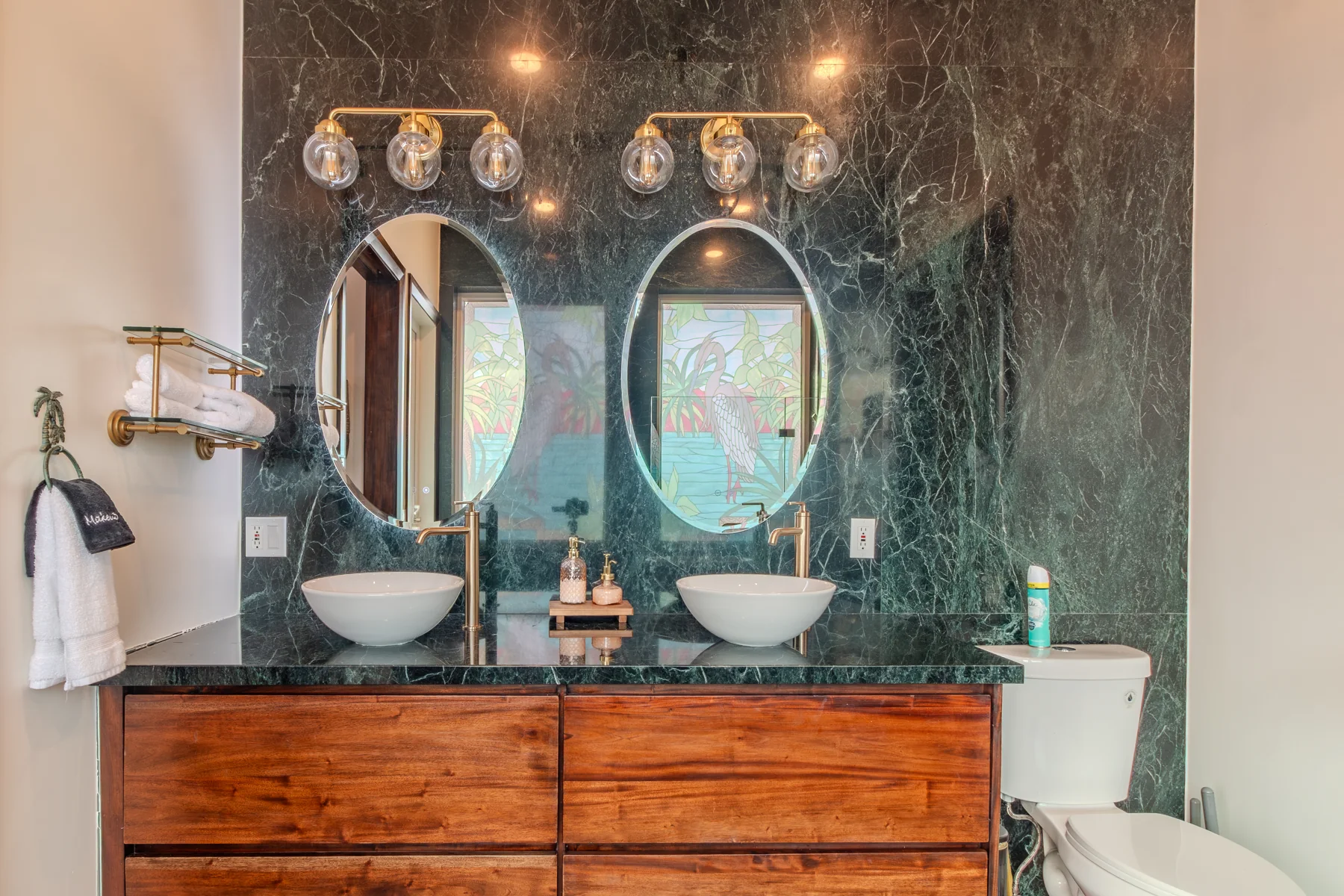 Double vanity and round mirrors in the shared green-stone bathroom
