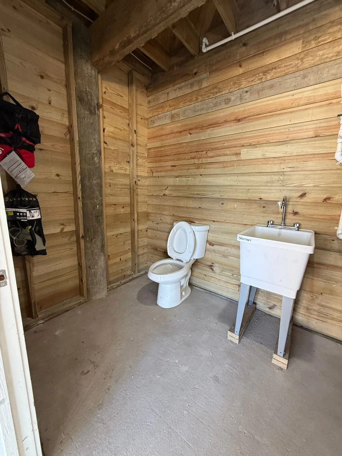 Utility bathroom sink and toilet against timber walls